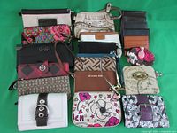 Overview of all 20 purses and wristlets arranged on a green background, showing various colors, patterns, and logos including Michael Kors and Disney Villains.