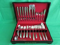 Full view of the open chest displaying the entire flatware set arranged in red felt slots