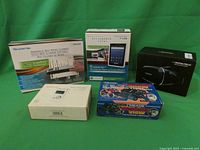 Overview of all five boxed items on green background, including handheld scanner, tablet, binoculars with camera, MP3 player, and virtual glasses