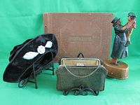Photo of black women's vintage hat, green textured vintage purse, old photo album, and Bob Cratchit and Tiny Tim figurine on display