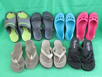 Five pairs of women's footwear including Crocs and sandals arranged on green background
