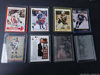 Photo showing 7 hockey cards laid out with visible players including Peter Stastny, Wayne Gretzky, and Cam Neely, all in protective sleeves.