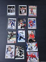 Photo showing 11 hockey trading cards arranged in grid on blue background, featuring various players and teams.
