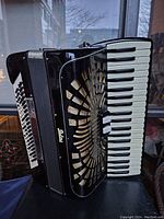 Front and side view of the black Galanti accordion showing keyboard, bass buttons, grille, and brand logo