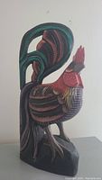 Side view of the 19 inch tall wooden rooster sculpture showing detailed carving and painted feathers.