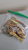 Bag containing assorted jewelry items including beads, chains, rings, and a pendant