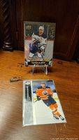 Hockey cards featuring Connor McDavid on a wooden surface, one on an easel stand and the other in a plastic sleeve