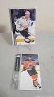 Two Connor McDavid hockey cards standing on plastic stands on a surface. One card has McDavid in a white jersey, the other in orange Edmonton Oilers jersey.