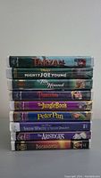 Stack of 9 Disney VHS tapes showing titles on spines including Tarzan, Mighty Joe Young, The Fox and the Hound, Pinocchio, The Jungle Book, Peter Pan, Snow White and the Seven Dwarfs, The Aristocats, Pocahontas.