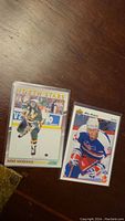 Front view of two Mike Modano rookie hockey cards showing action and portrait shots on a wooden surface.