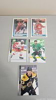 Top view of five NHL rookie player trading cards arranged on a light surface, showing front images of players in hockey gear.