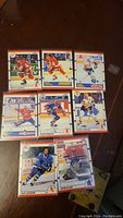 Top view of eight hockey cards featuring various NHL players on a wooden surface.