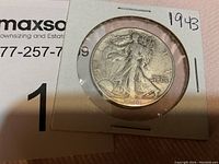 Front view of the 1943 Walking Liberty Half Dollar coin in a cardboard holder with clear plastic window.