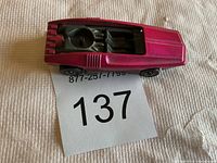 Top-down view of 1969 Hot Wheels Whip Creamer Redline diecast car showing metallic pink body, black interior and seating, and rear vents.
