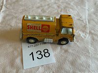 Yellow vintage metal toy truck with Shell branding, showing paint wear and top/down views.