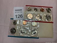 Two uncirculated coin sets from 1980 in original sealed packaging, one with blue border and one with red border.