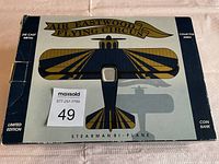 Box showing Air Eastwood Flying Circus Stearman Bi-Plane in blue and yellow, labeled die cast metal, coin bank, limited edition and collector series with lot number sticker.