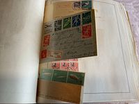 A photo showing stamps affixed to an album page, including an envelope attachment with stamps and postmarks, plus block of green stamps.