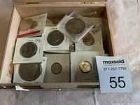 Wooden box containing various coins in holders and plastic sleeves with markings showing years and conditions.