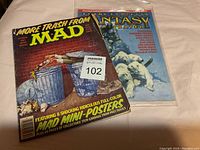 Front cover photo showing worn MAD magazine and Fantasy Illustrated magazine behind it