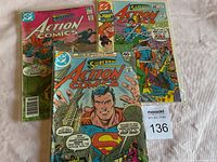 Three Superman Action Comics with varying cover designs and prices, displayed on a light surface