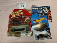 Johnny Lightning 1969 Camaro toy car in original blister pack with collectible storage tin, Hot Wheels Chevy Chevelle Special Edition car in blister pack, and Kellogg's Racing Mini-Car with Tony the Tiger packaging.