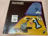 Front cover of the vinyl album 'Golden Biscuits' by Three Dog Night showing colorful artwork and title