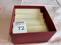 Red box filled with numerous envelopes or sleeves holding stamps, viewed from above.