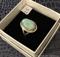 Sterling silver ring with a blue-green oval stone displayed in a white box with black interior, showing the front angle and size tag.
