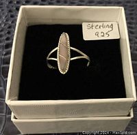 Front-facing close-up showing the pink oval stone and twisted rope bezel setting on sterling silver ring in a white jewelry box with black interior.