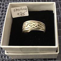 Front angled view of sterling silver ring with Celtic knot design in white jewelry box with black velvet interior. Small paper label reads 'sterling 925'.