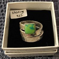 Sterling silver ring in box showing hammered texture and green stone.