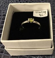 View of ring front showing green heart-shaped gemstone and 'Sterling 925' sticker on box