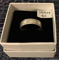 Sterling silver ring in white box, black interior, with a label 'sterling 925' visible on box lid.