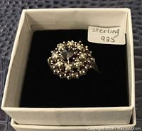 Top view of ring showing large central red stone, surrounded by smaller red and clear stones set in sterling silver.