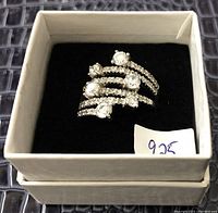 Sterling silver ring size 9 with multiple clear stones on a multi-row band, placed inside a white box with black interior and a handwritten 925 tag.