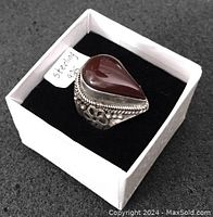 Large sterling silver ring with teardrop shaped polished brown stone, placed in a white box with black velvet interior