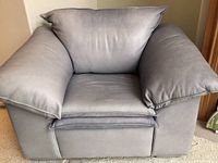 Front view of oversized cornflower blue faux leather armchair showing wide seat, back cushion, and padded armrests.