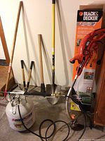 Photo showing various long-handled garden tools, Black & Decker trimmer and hedger, and AmeriGas propane cylinder with attached weed burner.