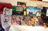 Overview of all tools and hardware laid out on table including red toolbox, thermometers, socket set, pliers, screwdrivers, Allen keys, adhesives, soldering materials.