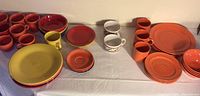 Overview photo showing assorted Fiesta Ware and Winsome plates, bowls, mugs, and cups in multiple colors including yellow, orange, red, and purple.