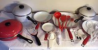 Full view of all cookware and utensils showing red skillets, white pots, and various utensils
