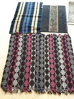 Six small rugs and mats arranged on a floor showing varying winter-themed colors and patterns including stripes, floral design, and geometric shapes.