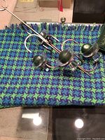 Vintage navy and green knit throw with hanging metal candle fixture featuring glass holders and green candles on top.