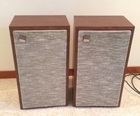 Pair of vintage Sony floor speakers showing wood veneer cabinet and fabric grill front.