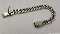 Full view of the Cuban link bracelet laid flat, showing the chain links and the clasp mechanism.