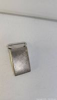 Front view of the rectangular silver belt buckle with attachment bar visible.