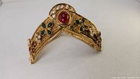 Front view showing V-shaped hinged bracelet segments with central red cabochon and enamel motifs