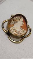 Close-up of antique handcarved cameo brooch showing female profile and gold frame