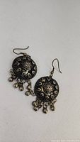 Front view of the antique handmade silver earrings showing their ornate floral design and dangling bells.